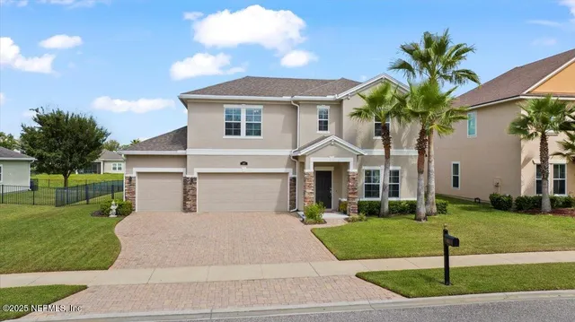 a front view of a house with a yard and potted plants
