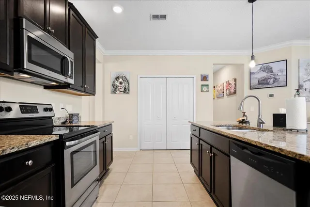 a kitchen with stainless steel appliances granite countertop a stove a sink and a microwave