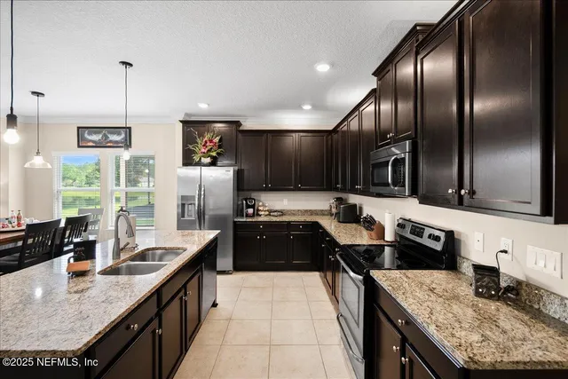 a kitchen with stainless steel appliances granite countertop a sink a stove and a refrigerator