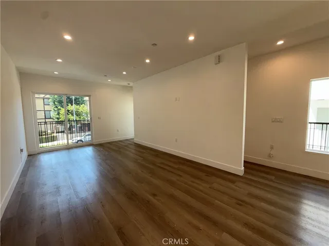 an empty room with wooden floor and a hallway