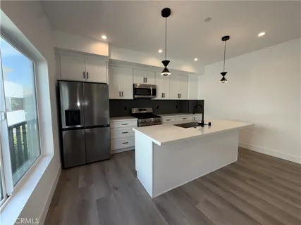 a view of kitchen with microwave a refrigerator and wooden floor