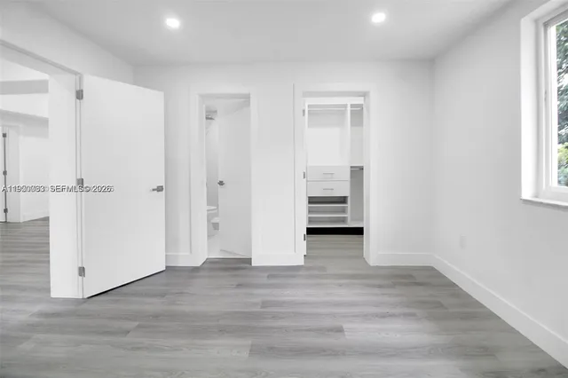 a view of empty room with wooden floor and window