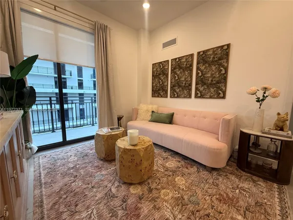 a living room with furniture a flat screen tv and a floor to ceiling window
