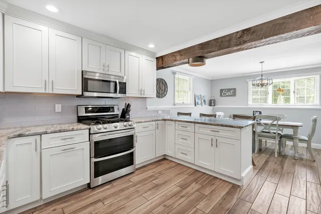 a kitchen with stainless steel appliances granite countertop a stove top oven a sink dishwasher a dining table and chairs with wooden floor