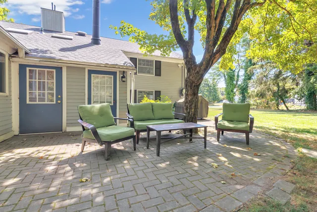 a view of a patio with table and chairs and a large tree