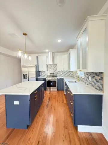 a kitchen with kitchen island a sink a stove and white cabinets