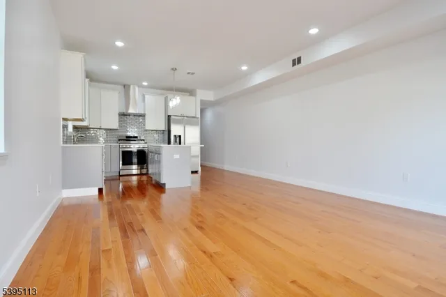 a kitchen with stainless steel appliances granite countertop a sink a stove a refrigerator and island with wooden floor