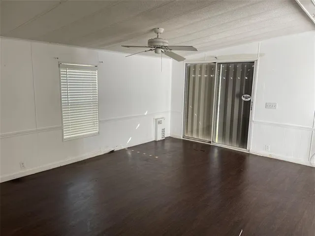 an empty room with wooden floor cabinet and windows