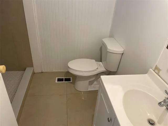 a white toilet sitting next to a white sink and vanity