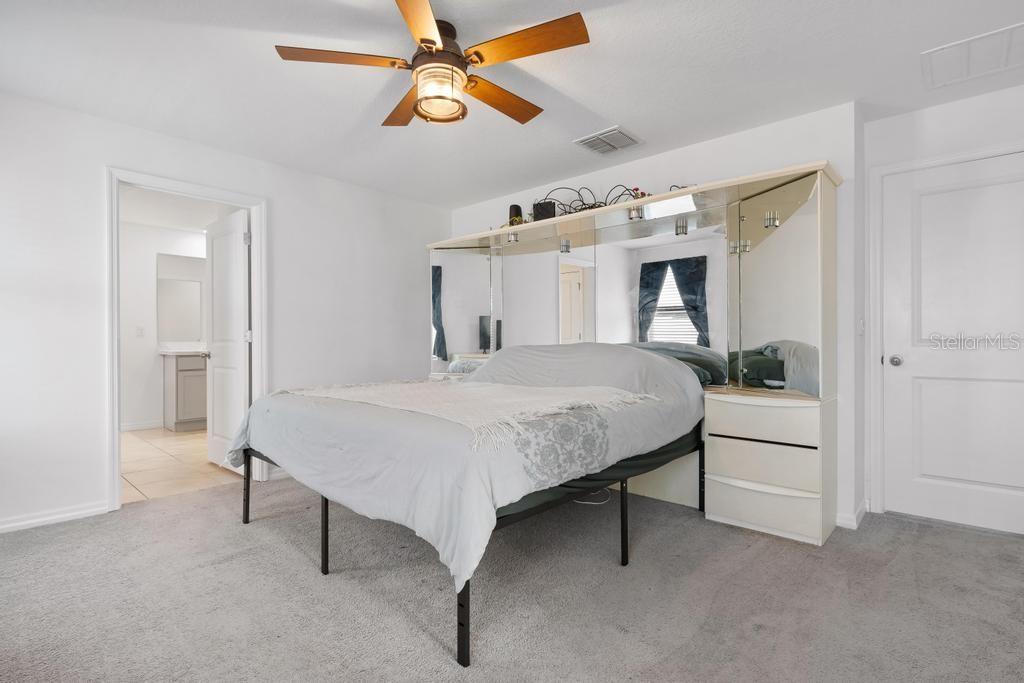 2986 Great Abaco Way Bradenton, FL 34208 - Photo 13 of 27 a bedroom with a bed and a chandelier