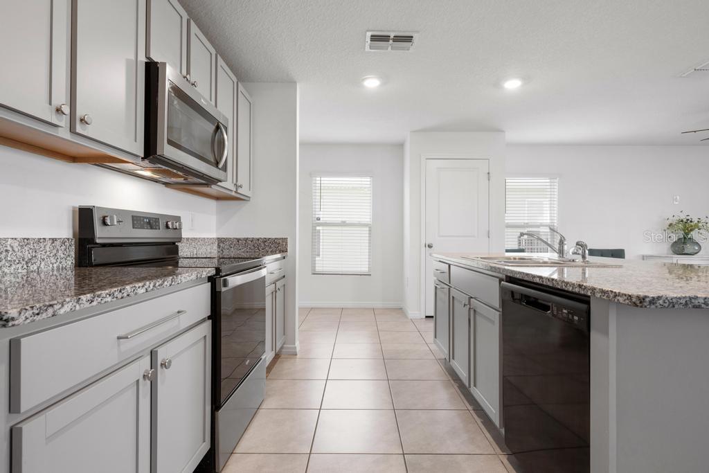 2986 Great Abaco Way Bradenton, FL 34208 - Photo 4 of 27 a kitchen with stainless steel appliances granite countertop a sink and dishwasher a stove top oven with wooden floor