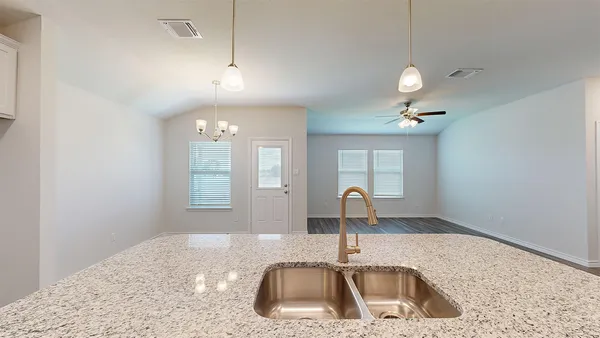 a large kitchen with kitchen island a stove a sink a refrigerator white cabinets and wooden floor