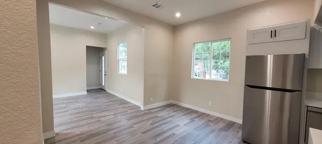 a view of a kitchen with a refrigerator and wooden floor
