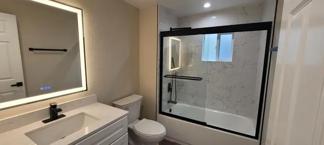 a bathroom with a bathtub shower sink vanity and toilet