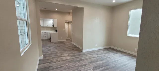 a view of a room with wooden floor electronic appliances and windows