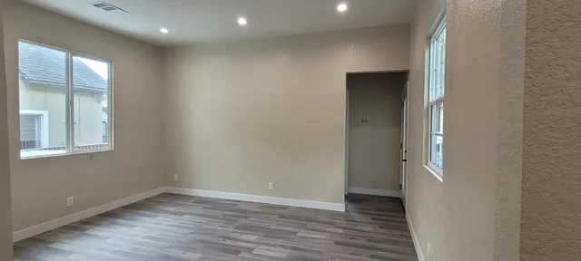 a view of an empty room with wooden floor and a window