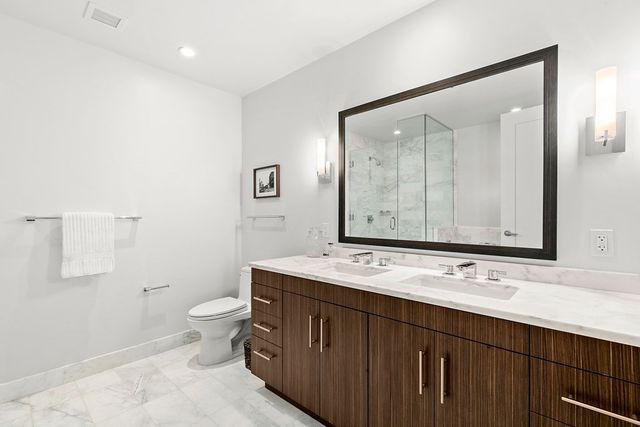 a bathroom with a double vanity sink a toilet and a mirror