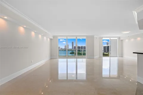 a view of an empty room with kitchen and window