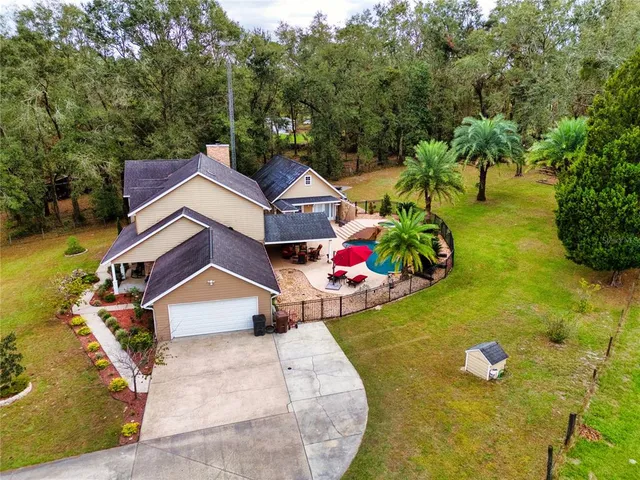 a aerial view of a house with swimming pool and large trees