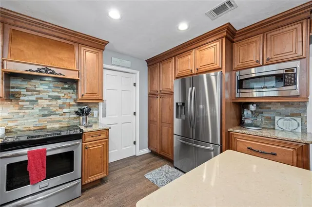a kitchen with stainless steel appliances granite countertop a sink and wooden cabinets