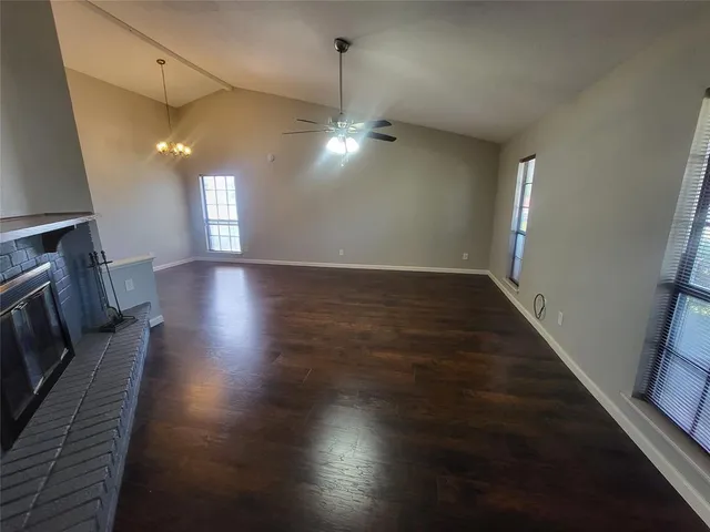 a view of an empty room with wooden floor fireplace and a window