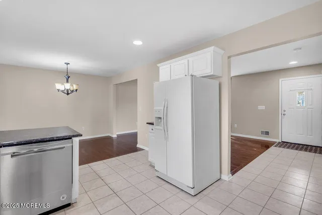 a view of a refrigerator in kitchen and white cabinets