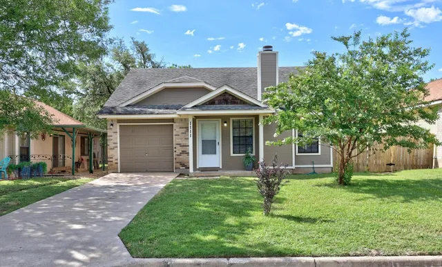 a front view of a house with a yard and large tree