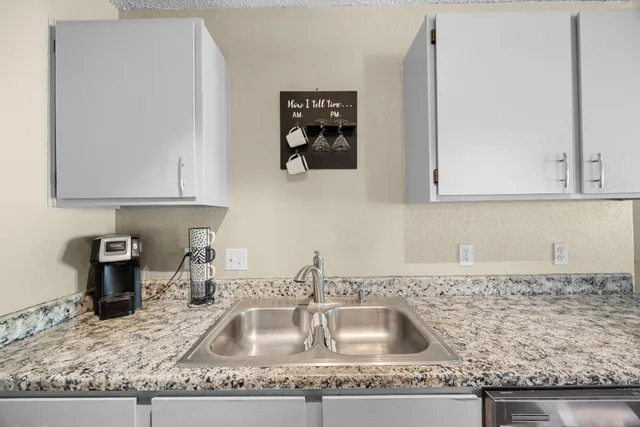 a kitchen with granite countertop a sink a stove and cabinets