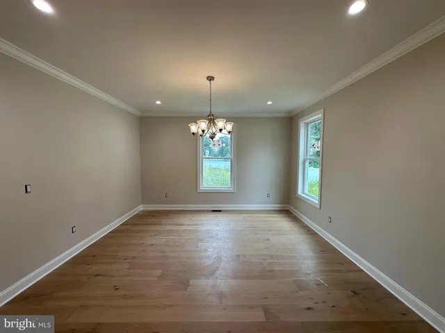 an empty room with chandelier fan and windows