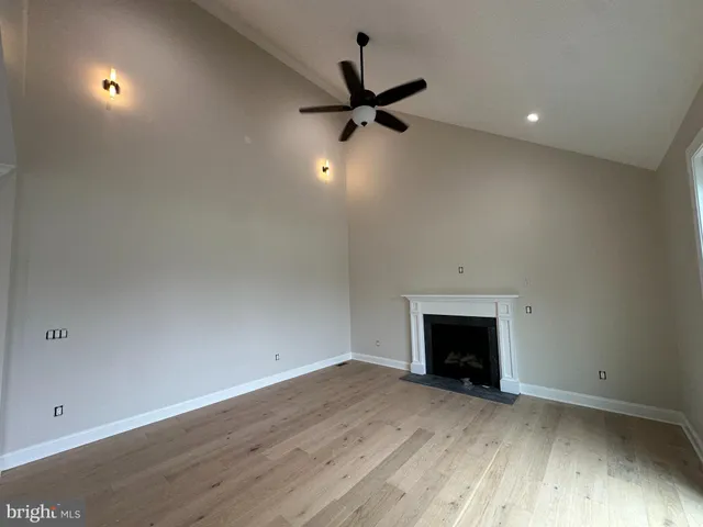 an empty room with wooden floor a ceiling fan and windows