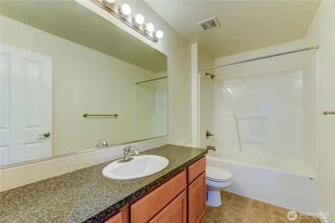 a bathroom with a granite countertop sink a toilet a mirror and shower