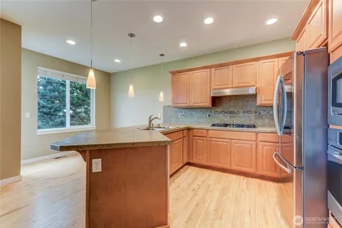 a kitchen with stainless steel appliances granite countertop a sink a stove and a refrigerator