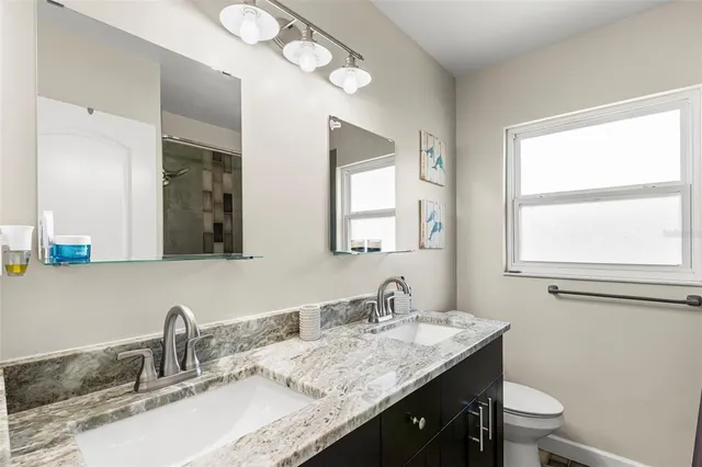 a bathroom with a granite countertop sink a toilet and a mirror