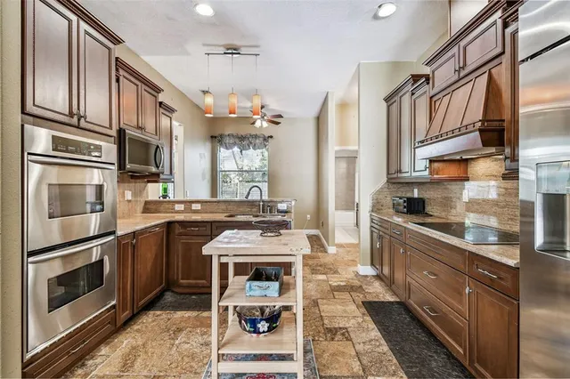 a kitchen with stainless steel appliances granite countertop a sink a stove and a refrigerator