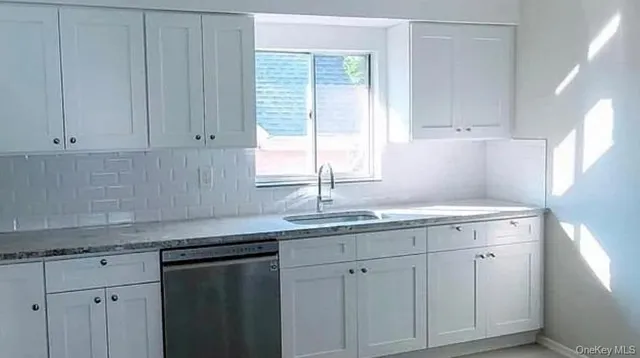 a kitchen with white cabinets and sink