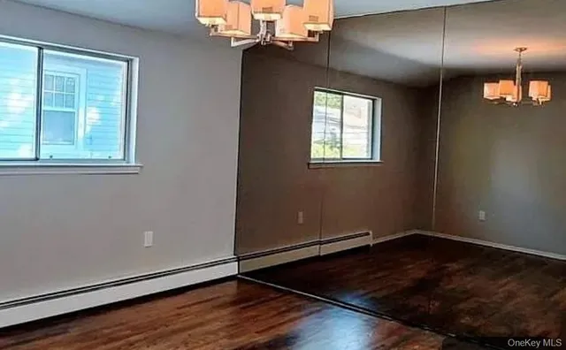 an empty room with wooden floor mirror and windows
