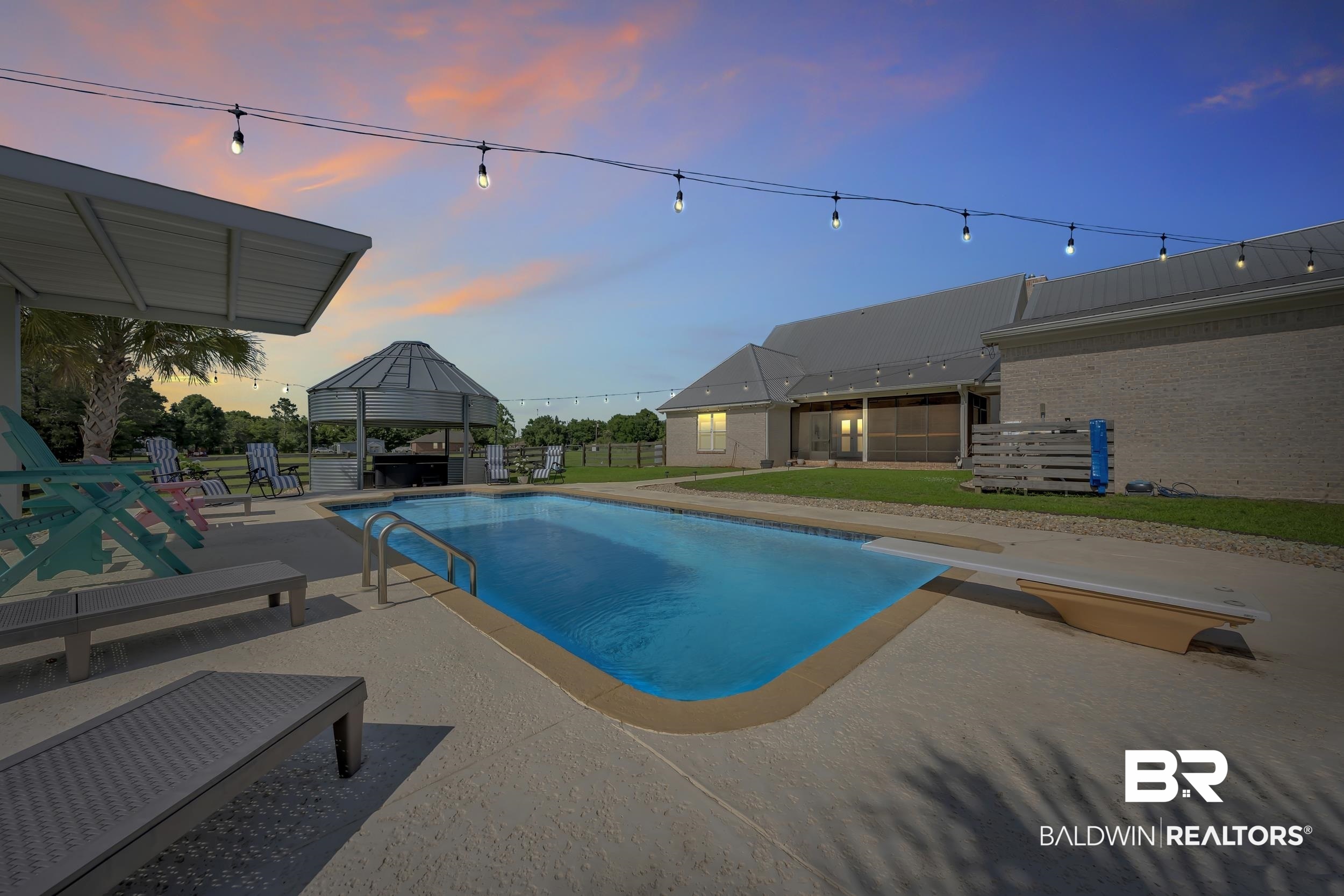 6576 Ranch Loop Road East Grand Bay, AL 36541 - Photo 4 of 39 Expansive backyard featuring a built-in swimming pool with a diving board, surrounding concrete patio, and a covered outdoor living area