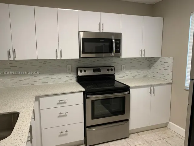 a kitchen with granite countertop white cabinets and stainless steel appliances