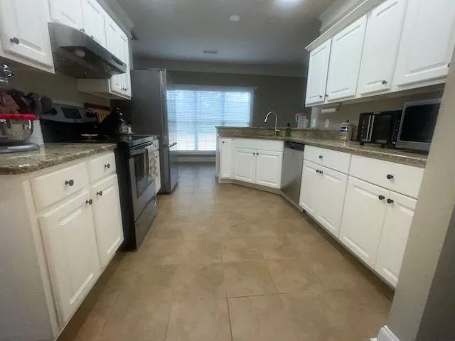 a kitchen with granite countertop cabinets stainless steel appliances and a sink