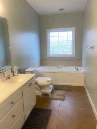 a spacious bathroom with a granite countertop toilet a sink and a bathtub