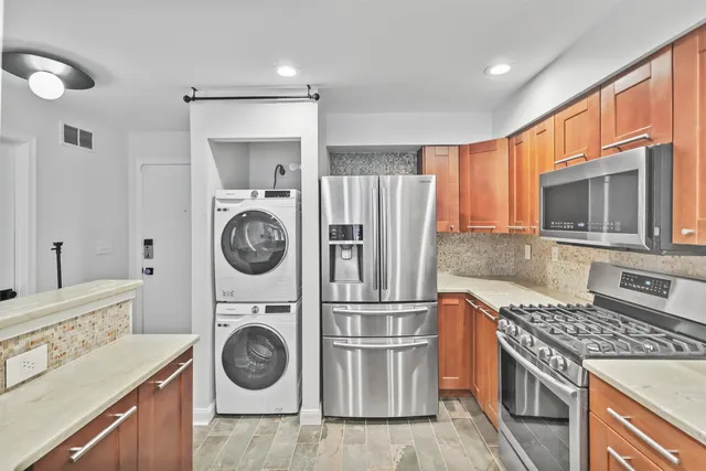 a kitchen with stainless steel appliances granite countertop a refrigerator a stove and a sink