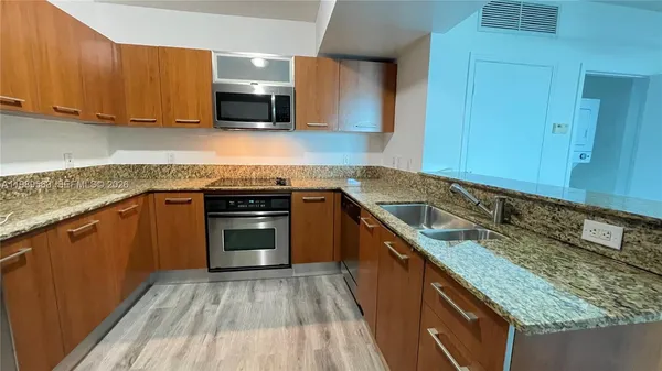 a kitchen with granite countertop a sink stove and cabinets