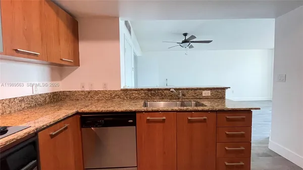 a kitchen with granite countertop a sink cabinets and stainless steel appliances