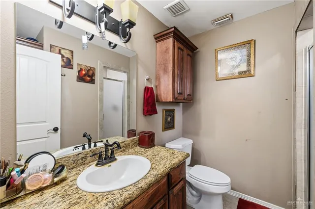 a bathroom with a granite countertop toilet a sink and a mirror
