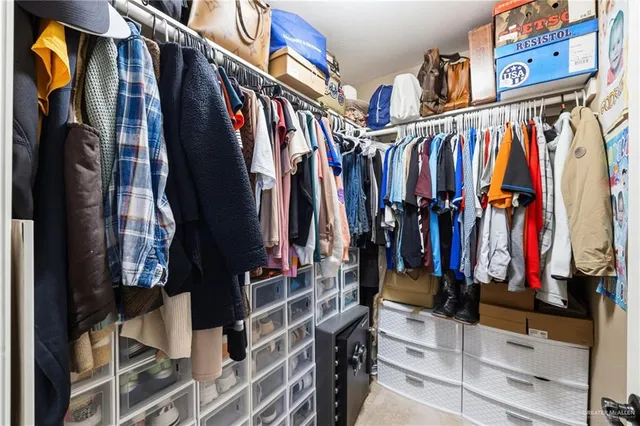 a view of walk in closet with clothes and shoes
