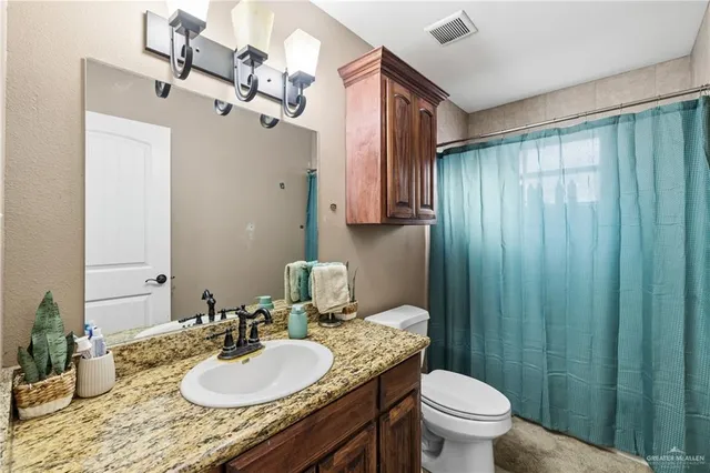 a bathroom with a granite countertop sink toilet mirror vanity and shower
