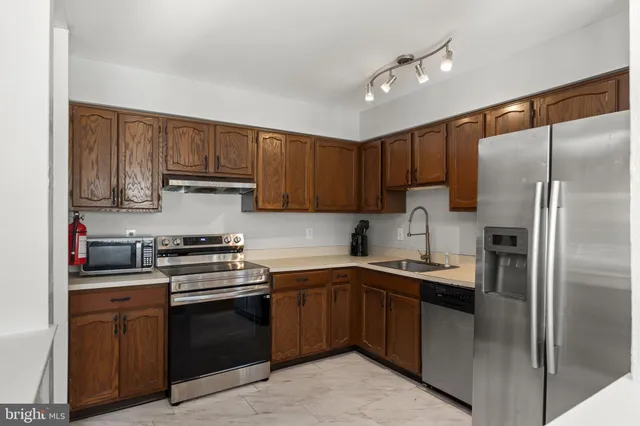 a kitchen with stainless steel appliances granite countertop a stove sink refrigerator and cabinets