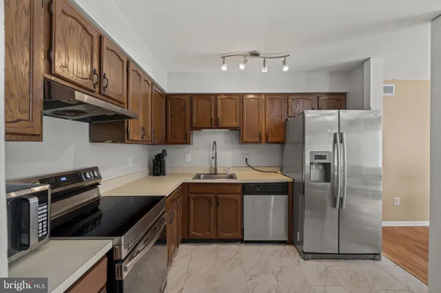 a kitchen with stainless steel appliances granite countertop a stove refrigerator and cabinets
