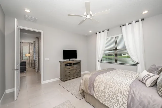 a bedroom with a bed flat screen tv and a large window