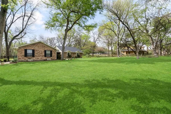 a view of a house with a big yard and large trees